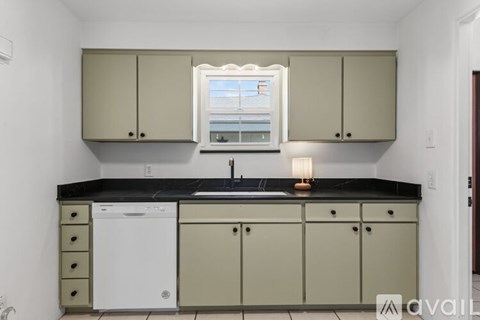 A kitchen with a white dishwasher and beige cabinets.