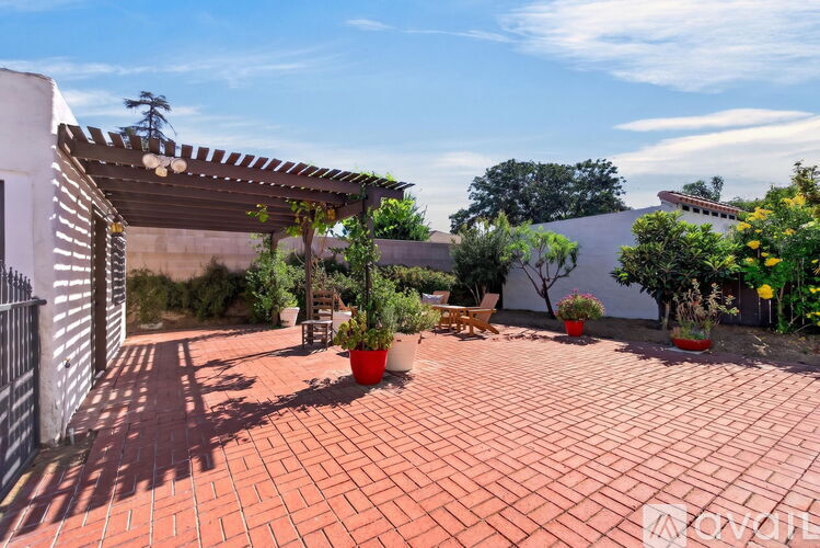 A patio with a white building and a tree in the background.