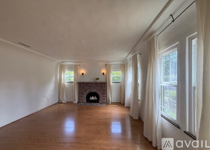 A spacious living room with a fireplace and wooden floors.