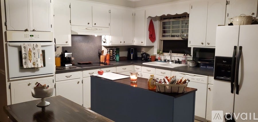 A kitchen with white cabinets and a blue island.
