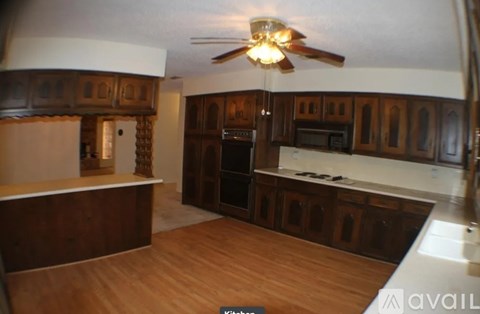 A kitchen with wooden cabinets and a fan.