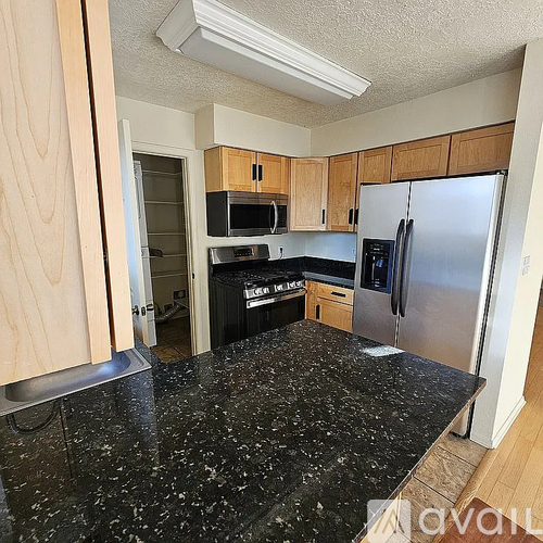 A kitchen with wooden cabinets and a black granite countertop.