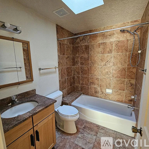 A bathroom with brown tiles and a skylight.