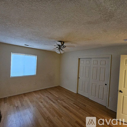 A room with a ceiling fan and wooden flooring.