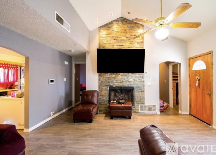 A living room with a stone fireplace and a flat screen TV mounted above it.