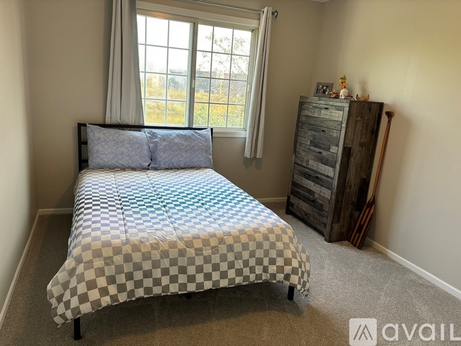 A bedroom with a bed and a wooden cabinet.