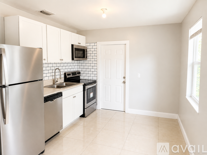 A kitchen with white cabinets and a stainless steel refrigerator.