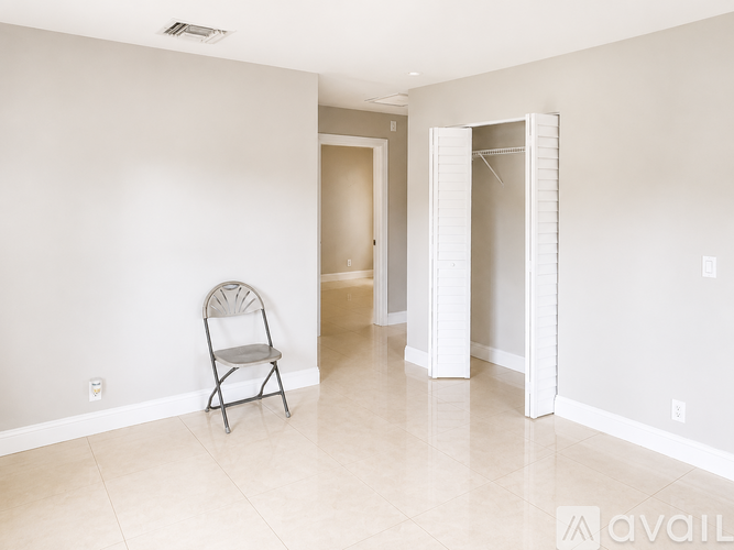 A room with a chair and a doorway leading to another room.