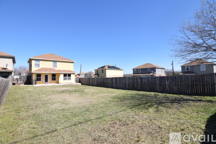 A grassy area with a fence and houses in the background.
