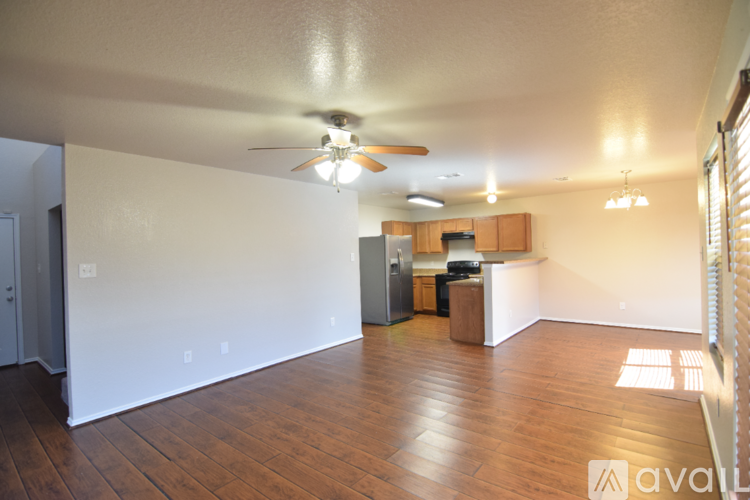 A living room with a ceiling fan and wooden floors.