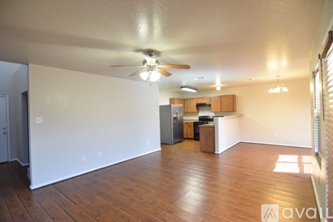 A living room with a ceiling fan and wooden floors.
