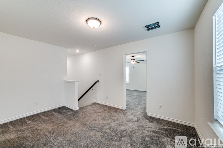 A spacious room with a carpeted floor and a staircase leading to another room.