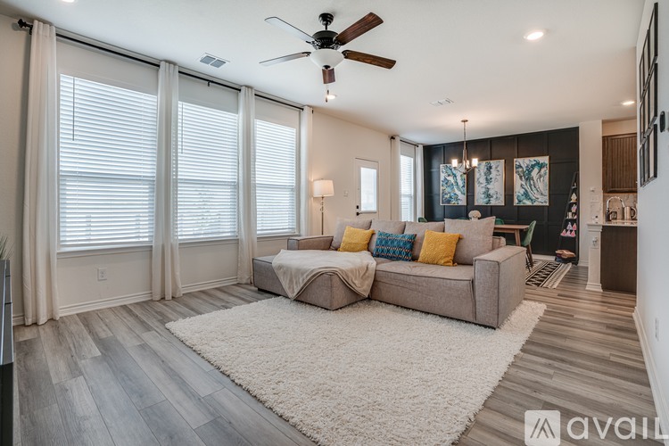 A spacious living room with a large couch and a ceiling fan.