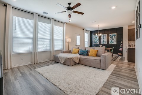 A spacious living room with a large couch and a ceiling fan.
