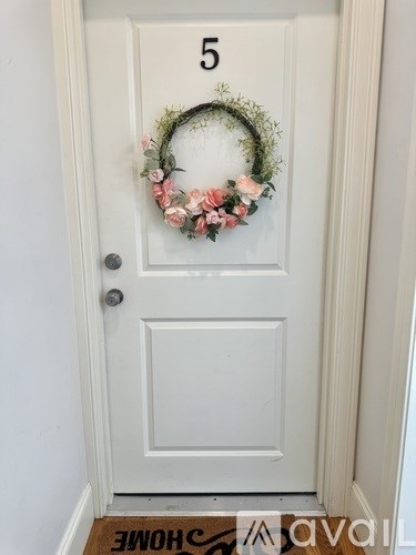 A white door with a number 5 and a floral wreath on it.