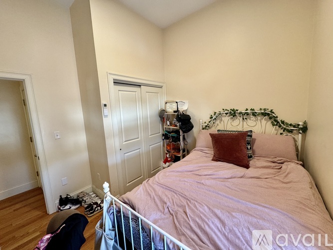 A bedroom with a bed, pillows, and a basket of greenery on the headboard.