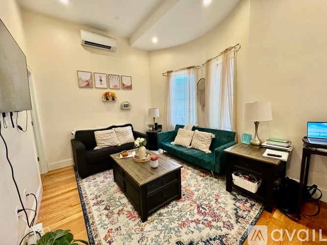 A living room with a green couch, a black couch, and a wooden coffee table.