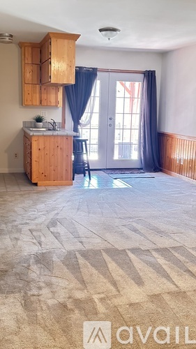 A room with a kitchenette and a dining area with a table and chairs.