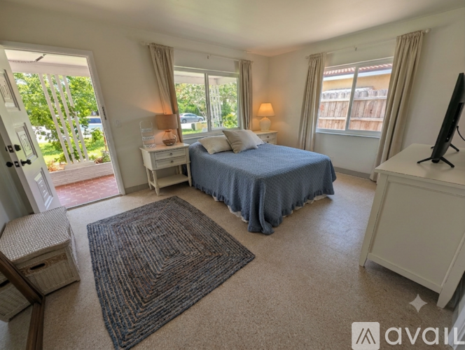 A bedroom with a large bed, a desk, and a television.