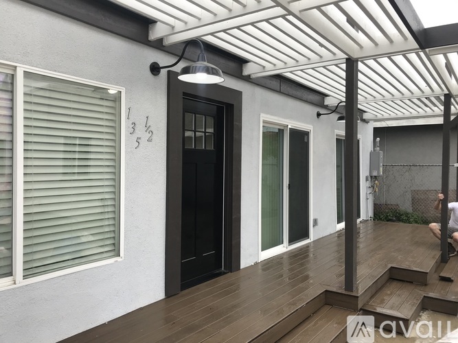 A balcony with a black door and a person standing on the right side.
