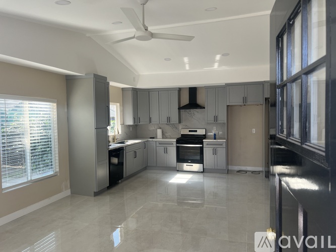 A spacious kitchen with a ceiling fan and modern appliances.