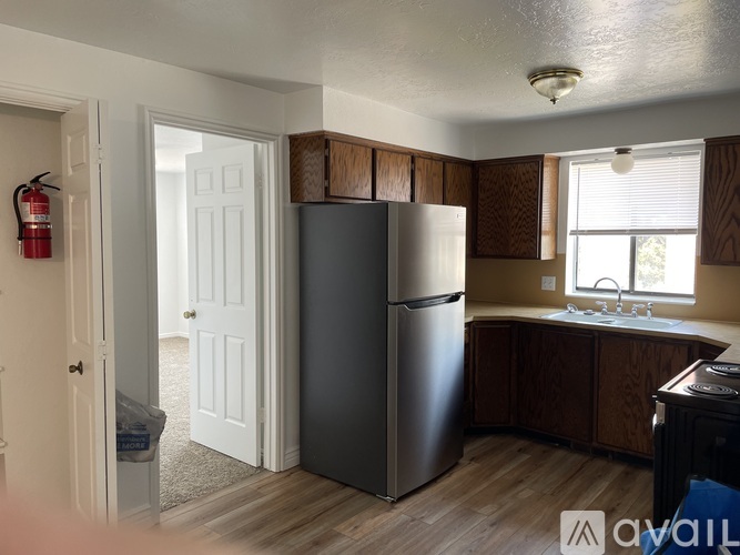 A kitchen with a black fridge and wooden cabinets.