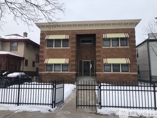 A two-story brick building with a black fence in front.