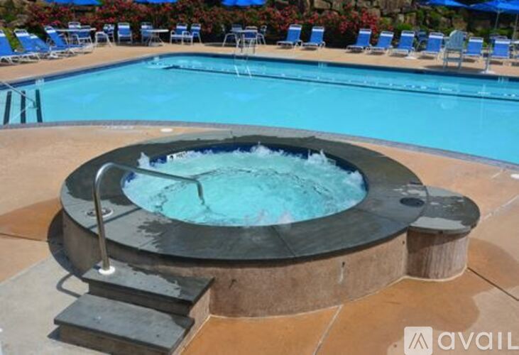 A hot tub sits in the middle of a pool surrounded by chairs.