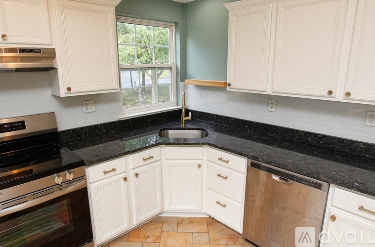 A kitchen with black granite countertops and white cabinets.
