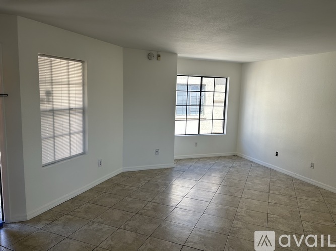 A spacious room with tile flooring and a window with blinds.