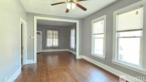 A room with a ceiling fan and hardwood floors.