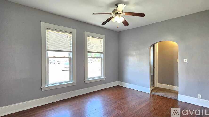 A room with a ceiling fan and two windows.
