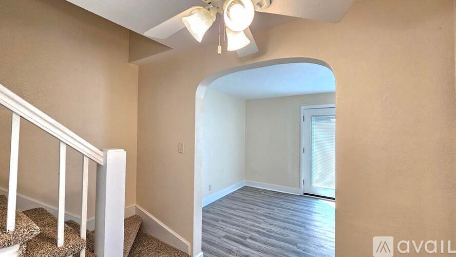 A room with a staircase and a door leading to another room.