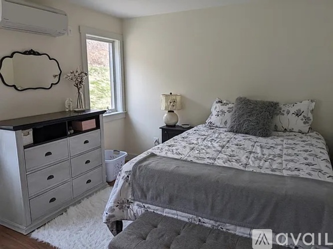 A bedroom with a bed, dresser, and window.