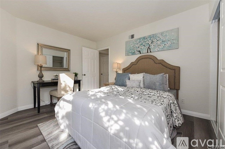 A bedroom with a large bed and a desk with a chair.