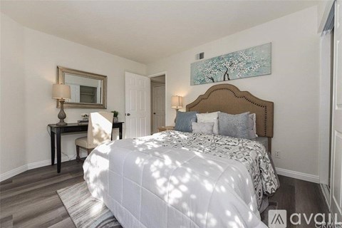 A bedroom with a large bed and a desk with a chair.
