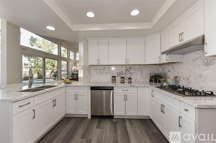 A kitchen with white cabinets and a marble countertop.