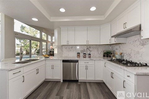 A kitchen with white cabinets and a marble countertop.