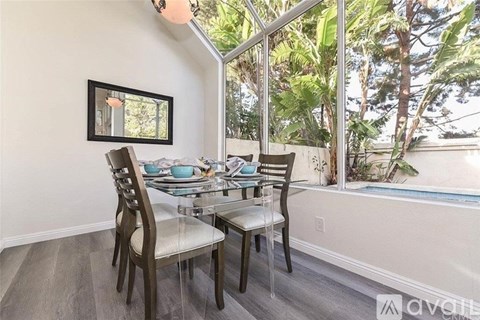 A dining room with a table set for two and a view of the outdoors.