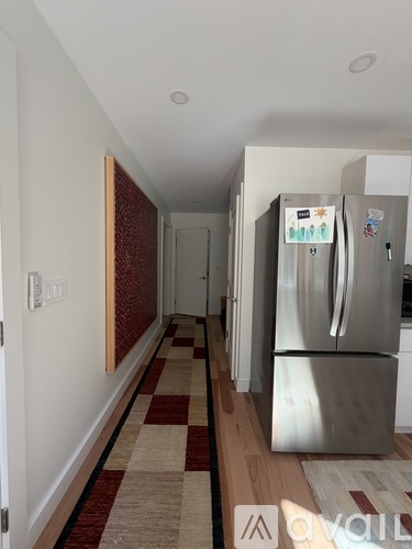 A kitchen with a stainless steel refrigerator and a checkered floor.