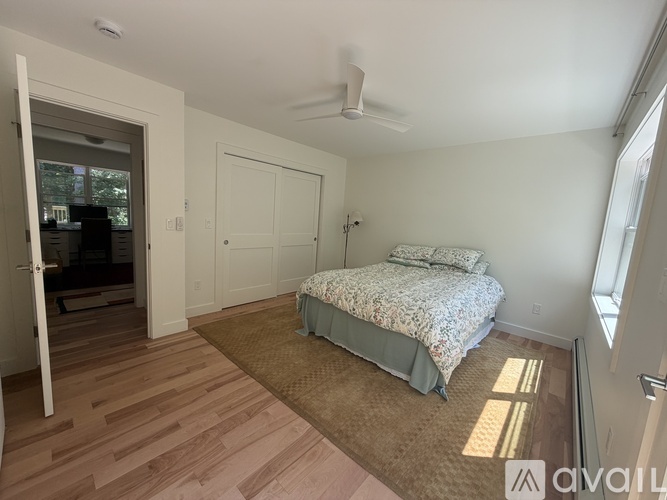 A bedroom with a bed, a ceiling fan, and a window.