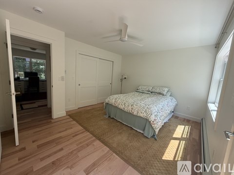 A bedroom with a bed, a ceiling fan, and a window.