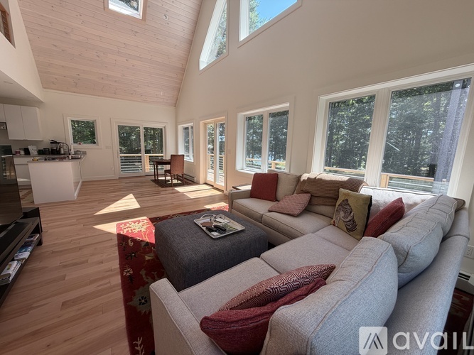 A living room with a grey couch and a red throw pillow.