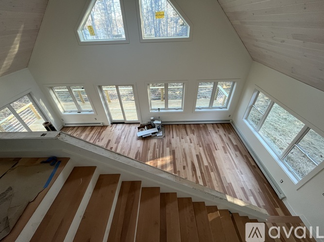 A wooden staircase leads up to a bright attic room with skylights.