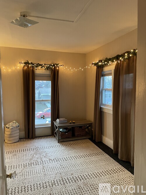 A room with a table and chairs in front of a window with curtains.