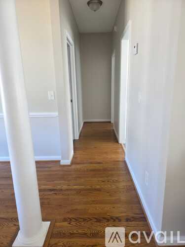 A hallway with wooden floors and white walls.