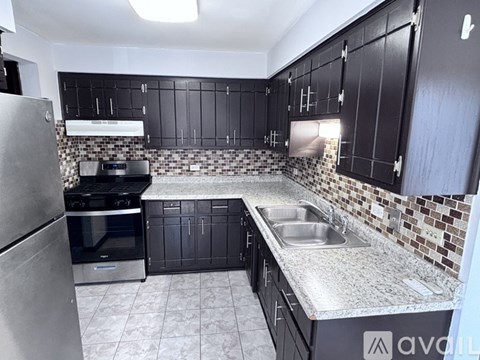 A kitchen with black cabinets and a stainless steel refrigerator.
