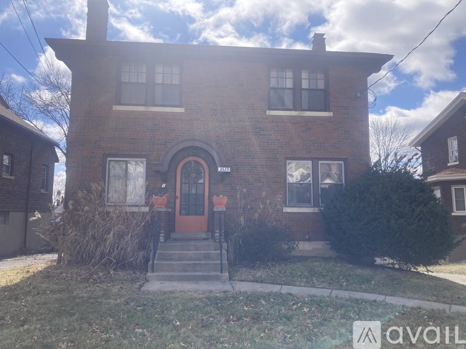 A brick house with a red door and a small front yard.