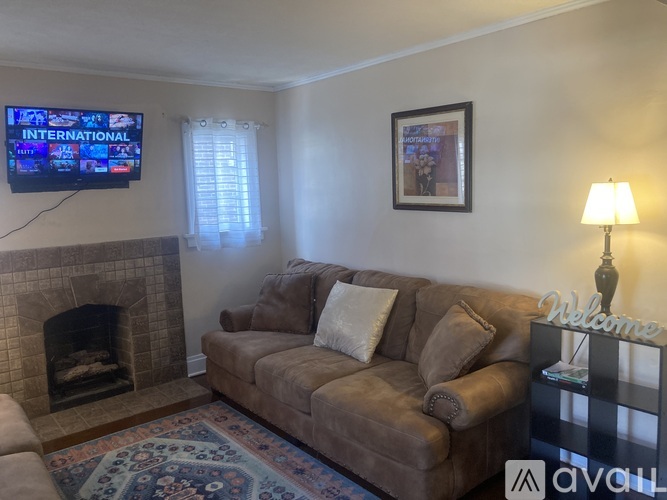 A living room with a couch, a fireplace, and a television displaying "INTERNATIONAL" on the screen.
