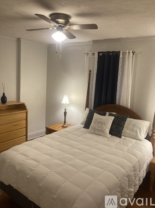 A bedroom with a bed, nightstand, and a ceiling fan.